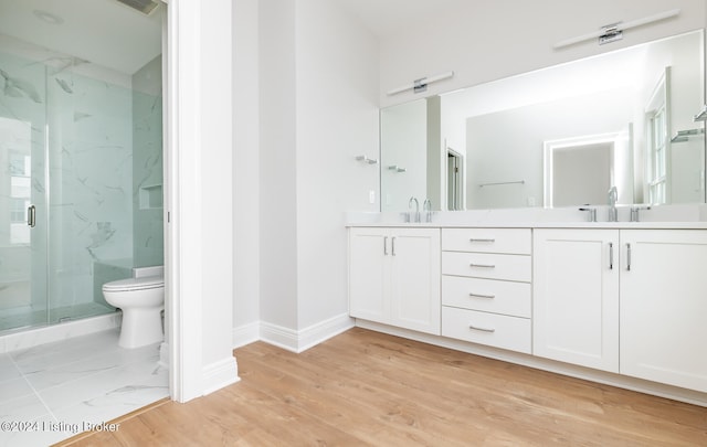 bathroom with toilet, a shower with door, hardwood / wood-style flooring, and dual bowl vanity