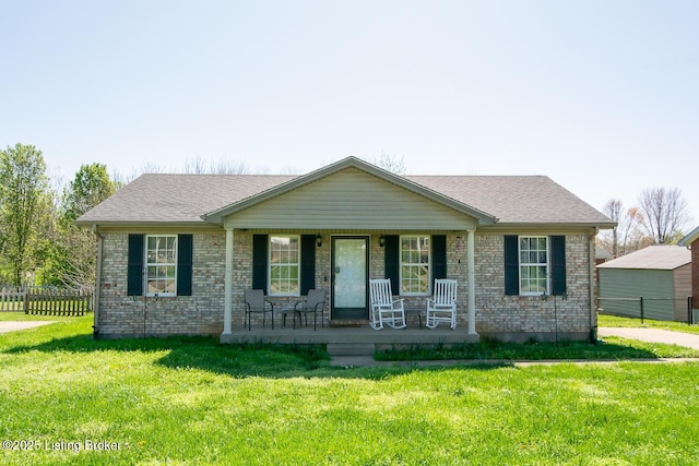 view of front facade with a porch, a front yard, fence, and brick siding