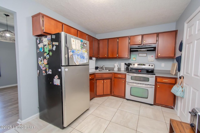 kitchen featuring light tile patterned floors, a sink, appliances with stainless steel finishes, a textured ceiling, and under cabinet range hood