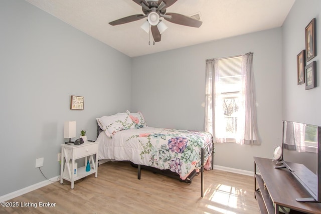 bedroom with baseboards, multiple windows, ceiling fan, and wood finished floors