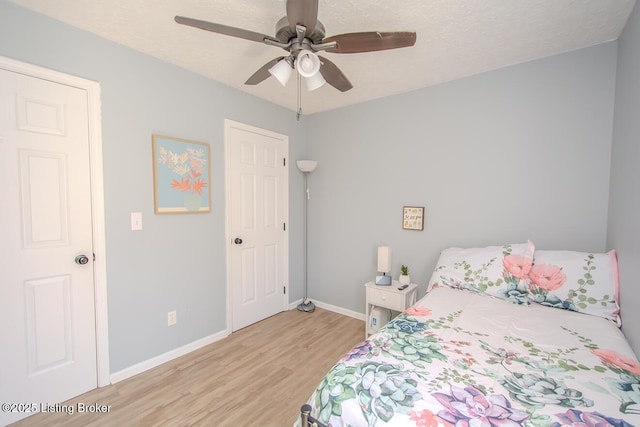 bedroom with light wood-style flooring, baseboards, a textured ceiling, and ceiling fan
