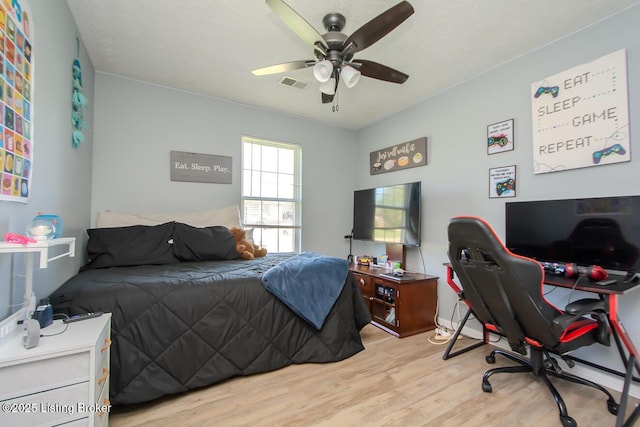 bedroom with light wood finished floors, visible vents, and ceiling fan