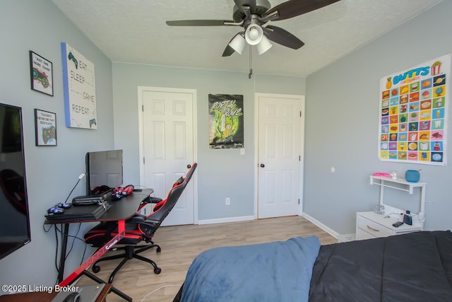 bedroom featuring baseboards, light wood finished floors, ceiling fan, and a textured ceiling