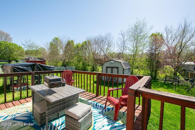 wooden terrace with an outdoor structure, a lawn, grilling area, a storage unit, and fence