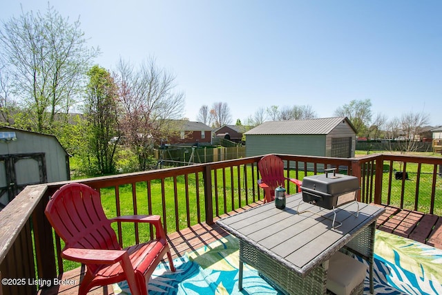 wooden terrace featuring a yard, a shed, fence, and an outdoor structure