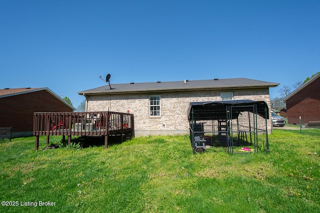 rear view of property with a yard, brick siding, and a wooden deck