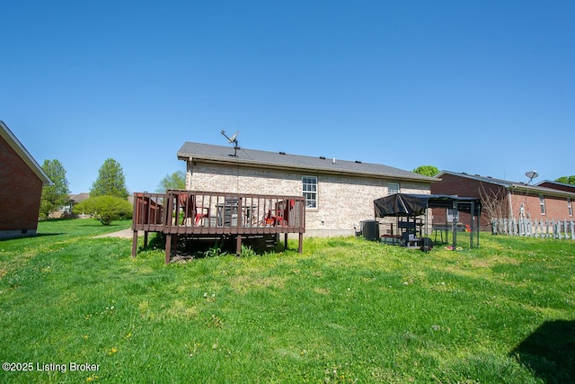 rear view of house featuring a lawn, a wooden deck, fence, and brick siding