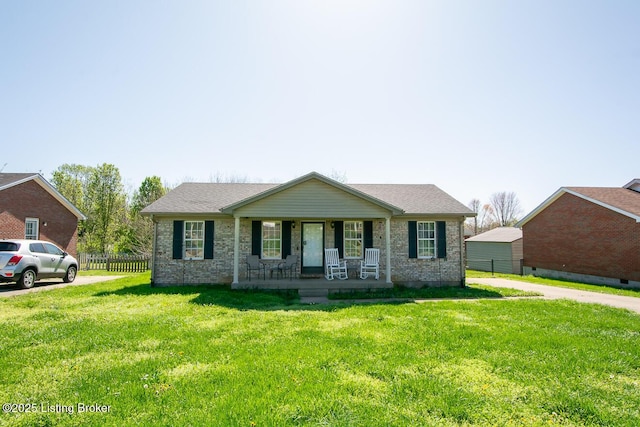 ranch-style home with covered porch, fence, a front lawn, brick siding, and a shingled roof