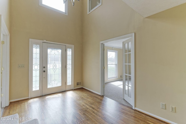 carpeted foyer with a towering ceiling and french doors