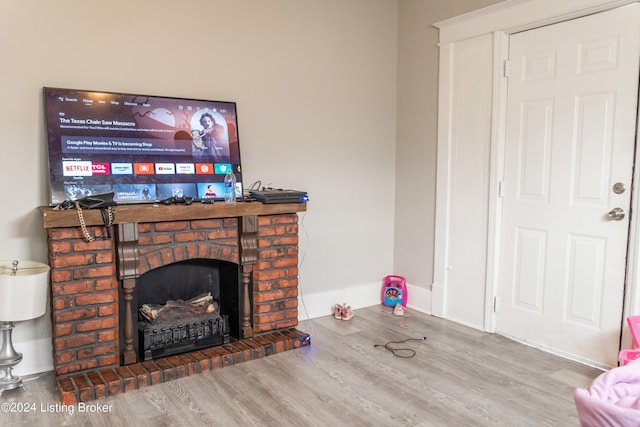 living room featuring a brick fireplace and wood-type flooring