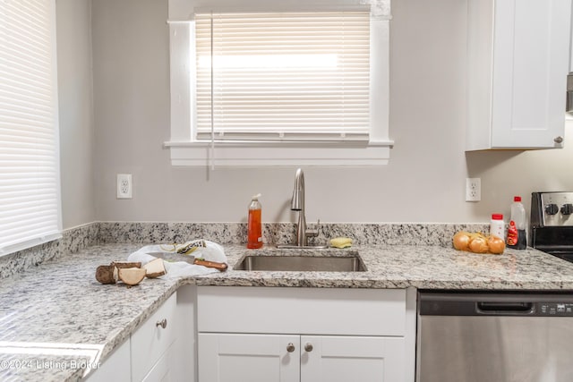 kitchen featuring dishwasher, white cabinetry, sink, and light stone counters