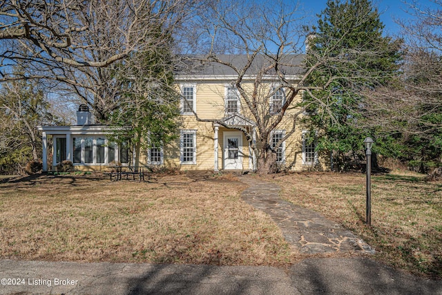 view of front of house with a sunroom and a front lawn