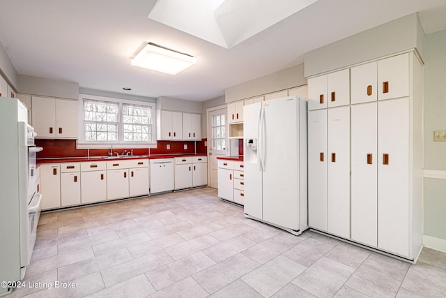 kitchen featuring white cabinets, light tile floors, white appliances, and sink