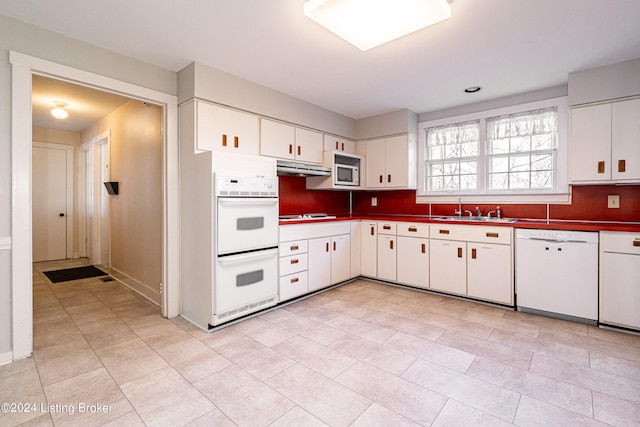 kitchen with white cabinets, light tile floors, white appliances, and sink