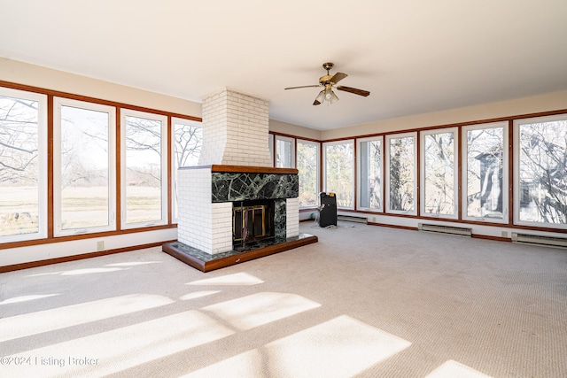 unfurnished living room with a brick fireplace, brick wall, ceiling fan, and light colored carpet