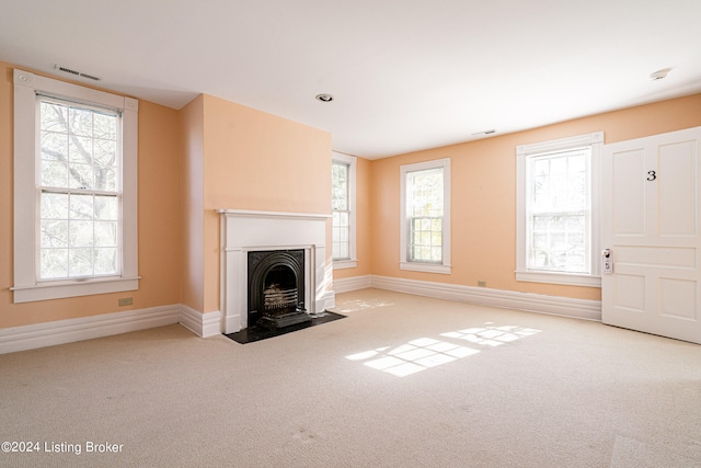 unfurnished living room featuring light carpet and a wealth of natural light