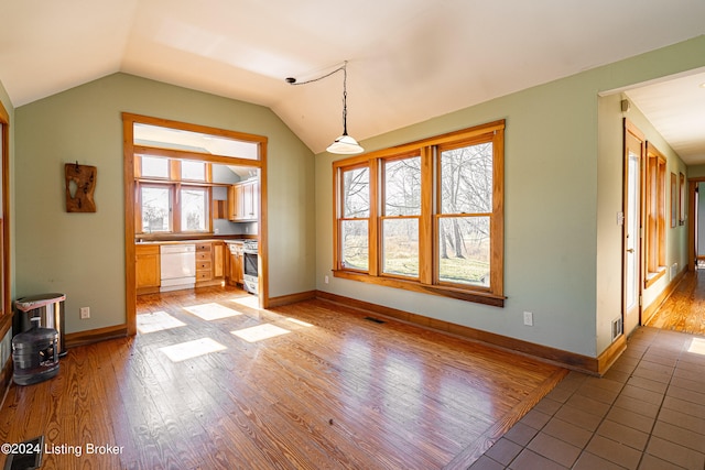 spare room with plenty of natural light, lofted ceiling, and dark tile flooring