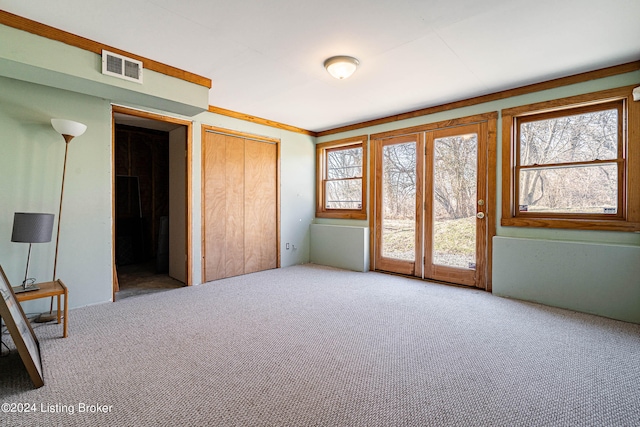 unfurnished bedroom with crown molding, light colored carpet, and access to outside