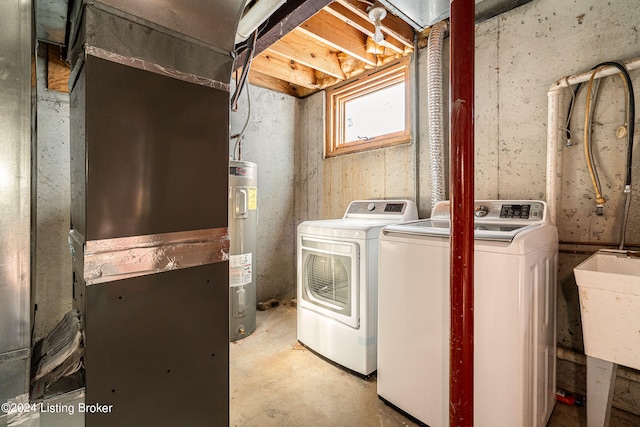 washroom featuring electric water heater, separate washer and dryer, and sink