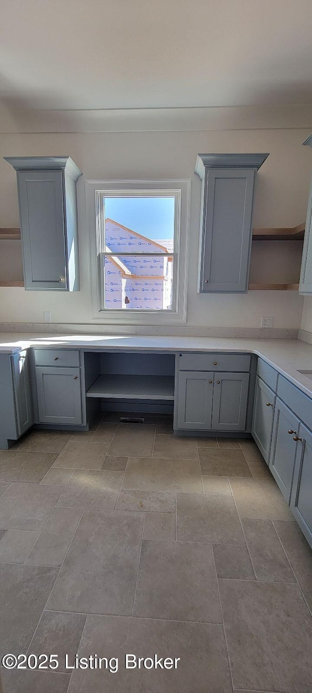 kitchen with open shelves, built in desk, gray cabinets, and light countertops