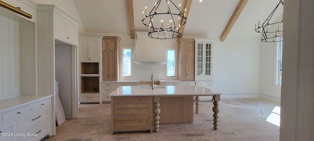 kitchen featuring decorative light fixtures, light countertops, glass insert cabinets, a kitchen island with sink, and a chandelier