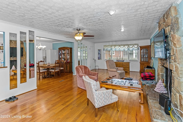 interior space with crown molding, light wood-type flooring, a fireplace, a textured ceiling, and ceiling fan with notable chandelier