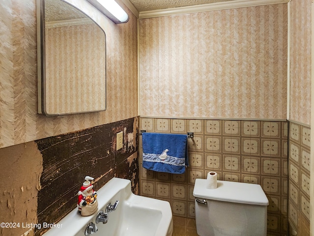 bathroom featuring crown molding, toilet, a textured ceiling, sink, and tile floors