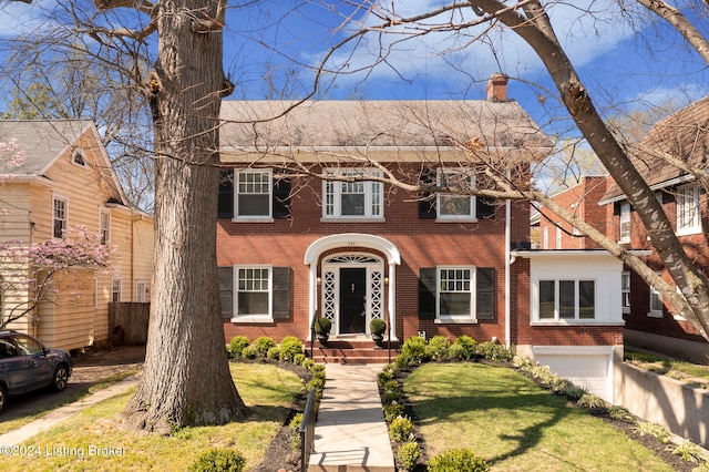 colonial inspired home featuring a front lawn and a garage