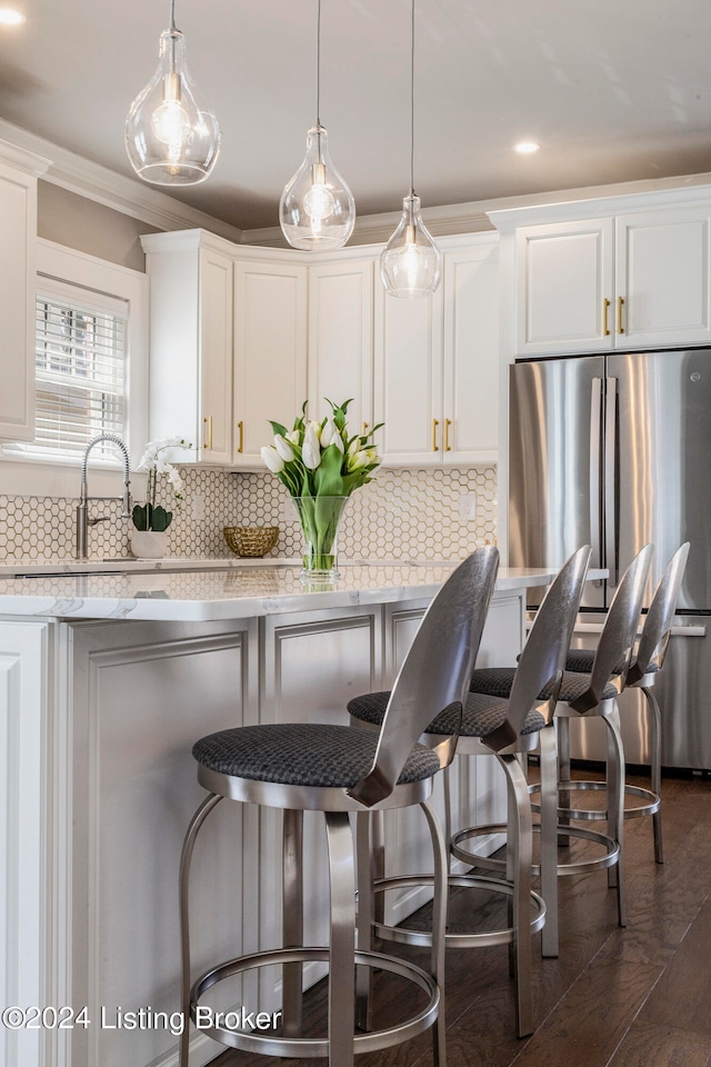 kitchen featuring a breakfast bar, pendant lighting, backsplash, and white cabinetry