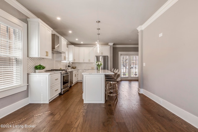 kitchen featuring a kitchen island, wall chimney range hood, a breakfast bar, appliances with stainless steel finishes, and dark hardwood / wood-style flooring