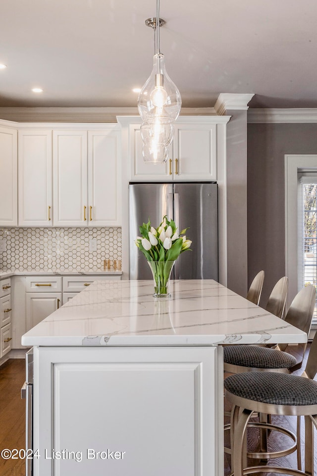 kitchen featuring stainless steel refrigerator, tasteful backsplash, a kitchen island, decorative light fixtures, and white cabinetry