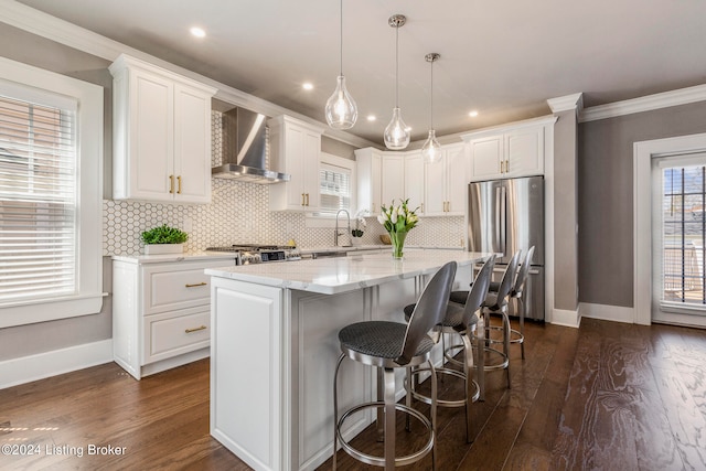 kitchen featuring dark hardwood / wood-style floors, wall chimney range hood, tasteful backsplash, white cabinetry, and a center island