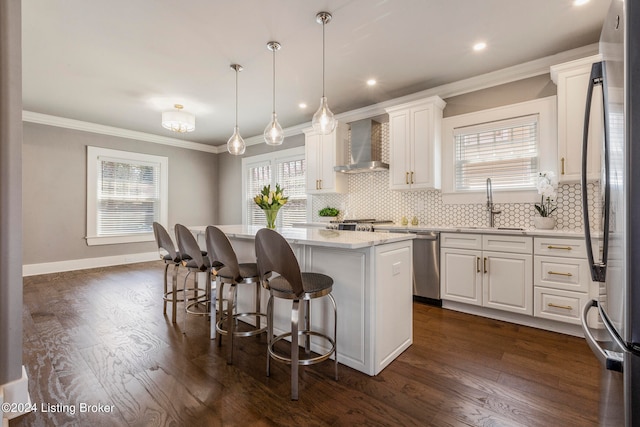 kitchen with hanging light fixtures, backsplash, dark wood-type flooring, wall chimney range hood, and a center island