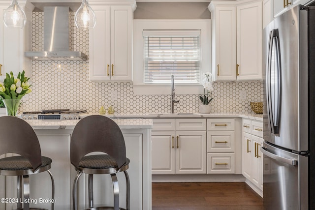 kitchen featuring stainless steel fridge, backsplash, decorative light fixtures, and wall chimney exhaust hood