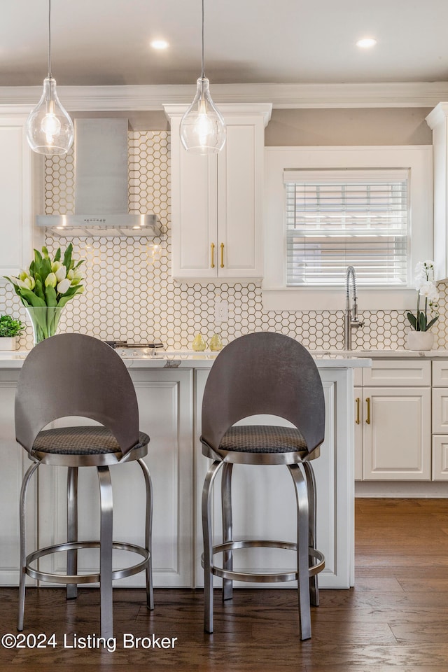 kitchen featuring white cabinets, wall chimney exhaust hood, and tasteful backsplash