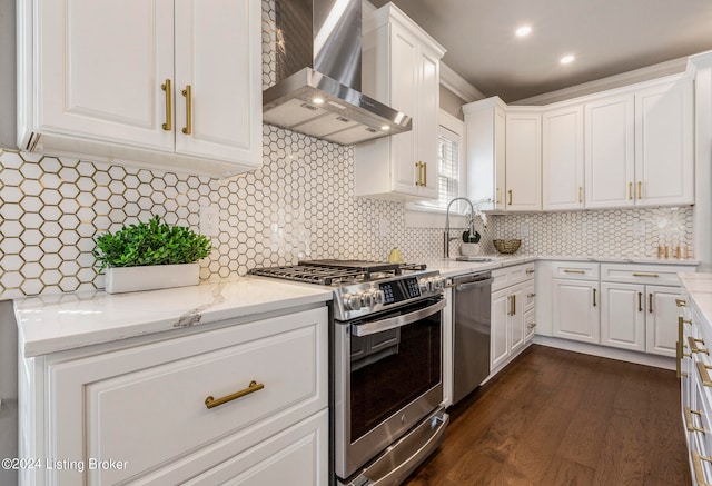 kitchen with light stone counters, white cabinets, appliances with stainless steel finishes, dark wood-type flooring, and wall chimney range hood