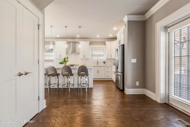 kitchen featuring wall chimney range hood, a breakfast bar area, a healthy amount of sunlight, and dark wood-type flooring