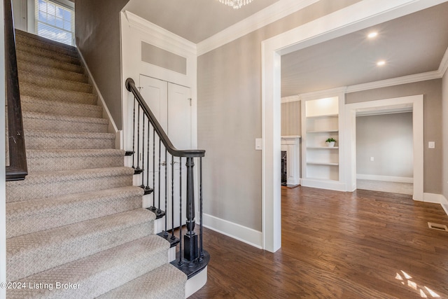 stairway with built in features, dark hardwood / wood-style floors, and ornamental molding