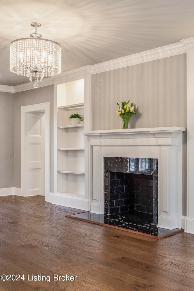 unfurnished living room featuring built in features, a high end fireplace, dark hardwood / wood-style flooring, and an inviting chandelier