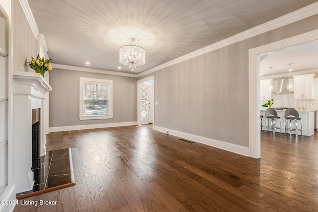 unfurnished living room with a chandelier, dark wood-type flooring, and ornamental molding