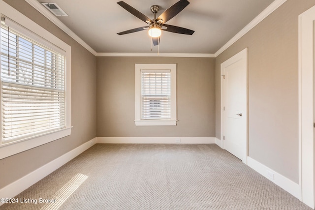 empty room with ceiling fan, crown molding, and light colored carpet