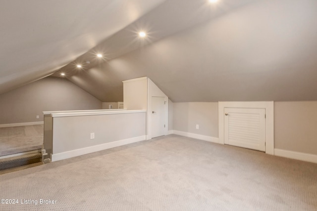 additional living space featuring light carpet and vaulted ceiling