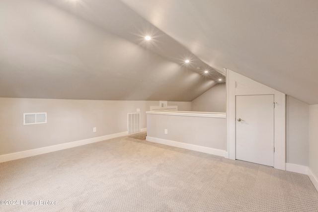 additional living space featuring light colored carpet and vaulted ceiling