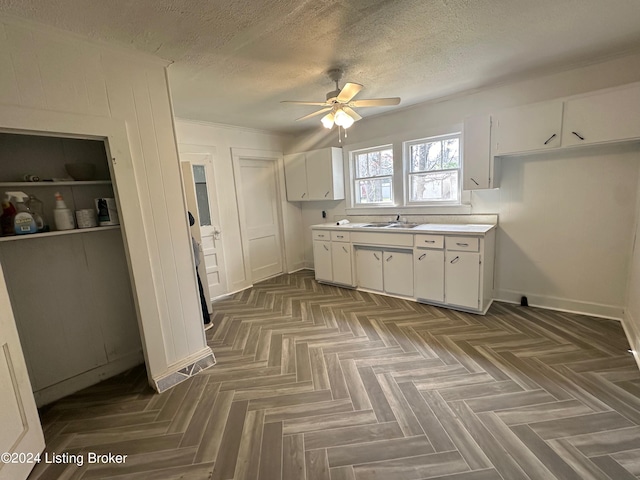 kitchen featuring white cabinets, sink, ceiling fan, and dark parquet flooring