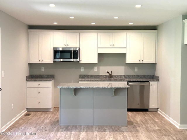 kitchen featuring sink, light wood-type flooring, white cabinetry, light stone countertops, and stainless steel appliances