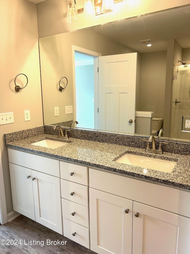 bathroom featuring wood-type flooring, toilet, a shower with shower door, and vanity