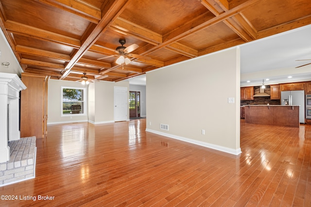 unfurnished living room with beamed ceiling, decorative columns, light wood-type flooring, coffered ceiling, and ceiling fan