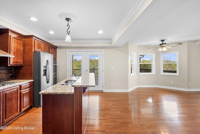 kitchen featuring a kitchen island with sink, stainless steel appliances, sink, light hardwood / wood-style floors, and ceiling fan