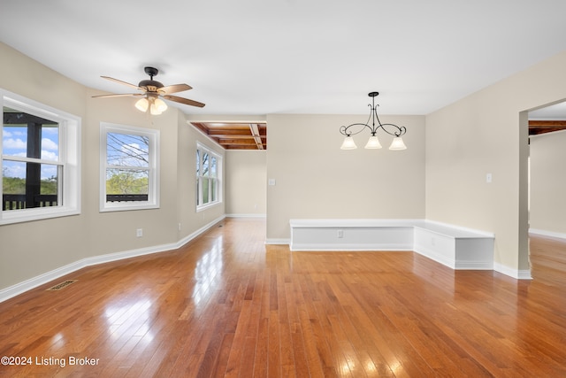 unfurnished room featuring ceiling fan with notable chandelier and light wood-type flooring