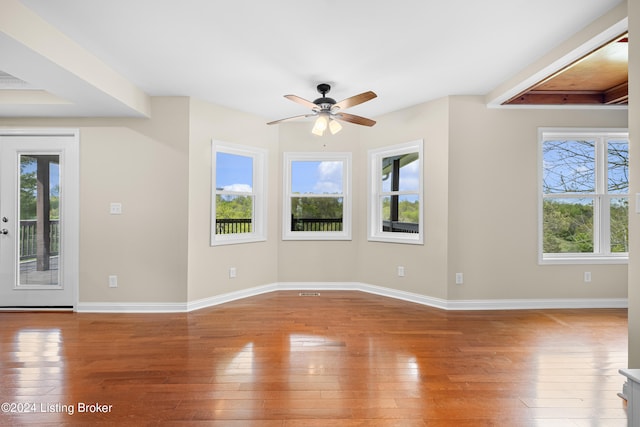 unfurnished room with a healthy amount of sunlight, ceiling fan, and hardwood / wood-style flooring